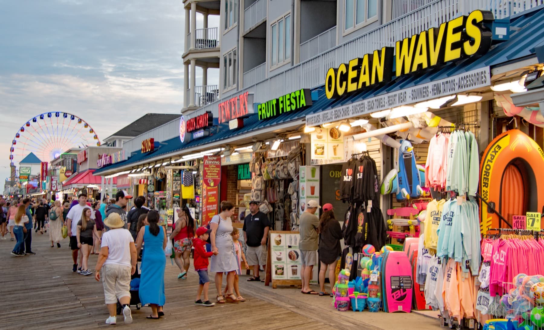 A wide view of the Ocean City Maryland Boardwalk with shops, benches, beach, and Atlantic sky